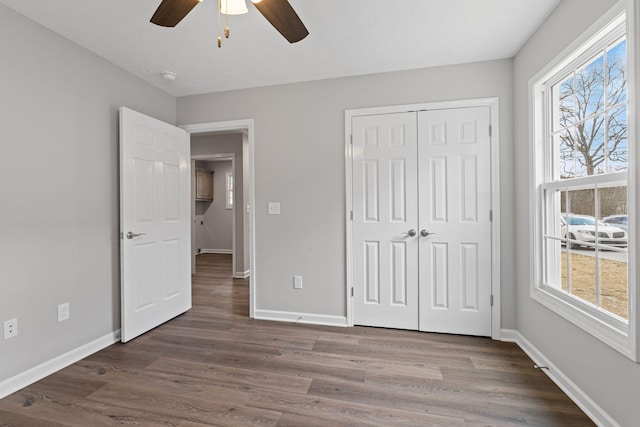 unfurnished bedroom with multiple windows, dark hardwood / wood-style flooring, a closet, and ceiling fan