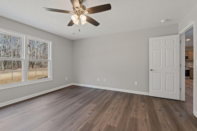 unfurnished room with ceiling fan, dark hardwood / wood-style flooring, and a textured ceiling