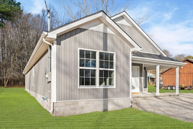 view of side of property featuring a lawn and covered porch