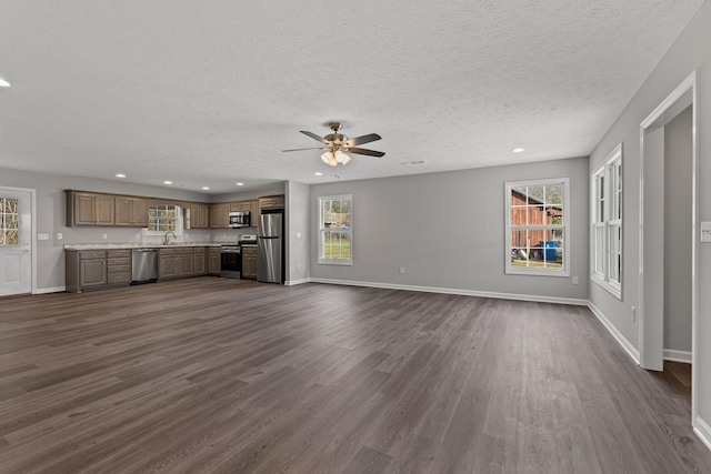 unfurnished living room featuring a textured ceiling, dark hardwood / wood-style floors, ceiling fan, and sink