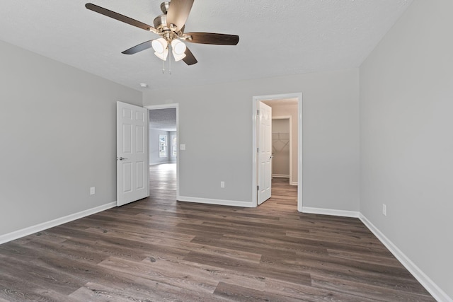 unfurnished bedroom with ceiling fan, dark hardwood / wood-style floors, a spacious closet, and a textured ceiling