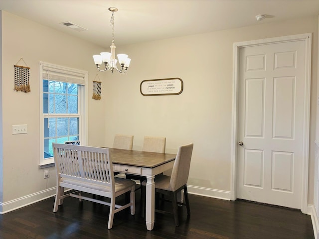 dining room with dark wood-type flooring and a chandelier