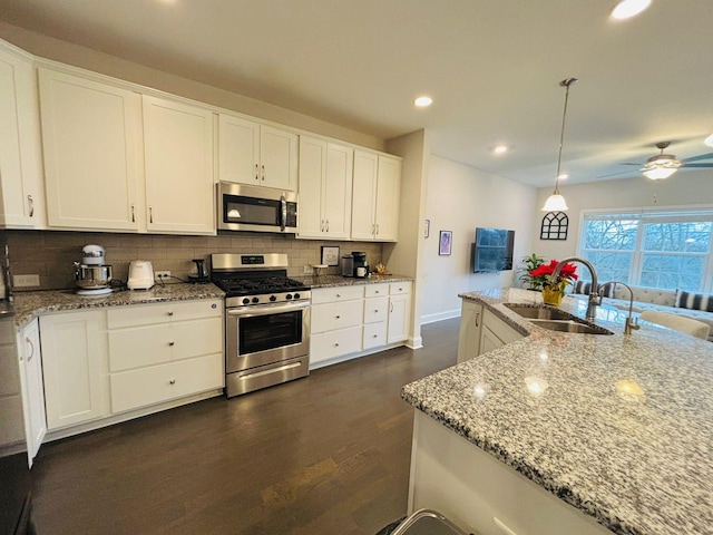 kitchen featuring pendant lighting, sink, light stone countertops, appliances with stainless steel finishes, and white cabinets