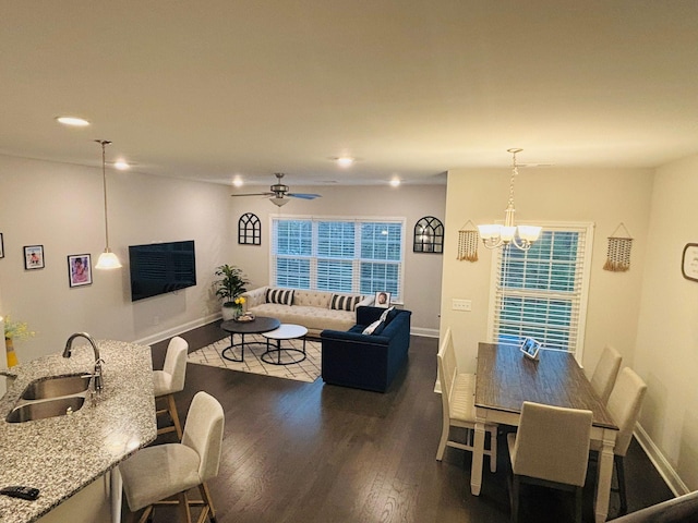 dining area featuring dark wood-type flooring, sink, and ceiling fan with notable chandelier