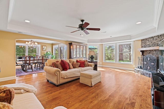 living room featuring a healthy amount of sunlight, a raised ceiling, wood-type flooring, and a fireplace