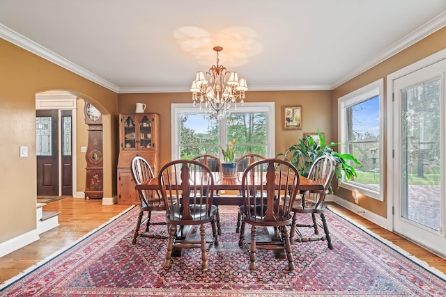 dining space featuring crown molding, light wood-type flooring, and a notable chandelier