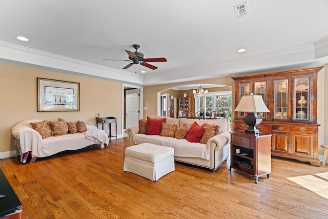 living room with ceiling fan with notable chandelier, light hardwood / wood-style floors, and ornamental molding