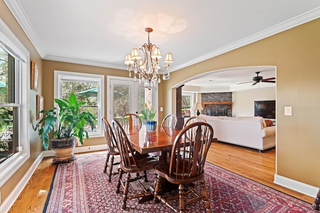 dining area with ceiling fan with notable chandelier, hardwood / wood-style flooring, plenty of natural light, and crown molding