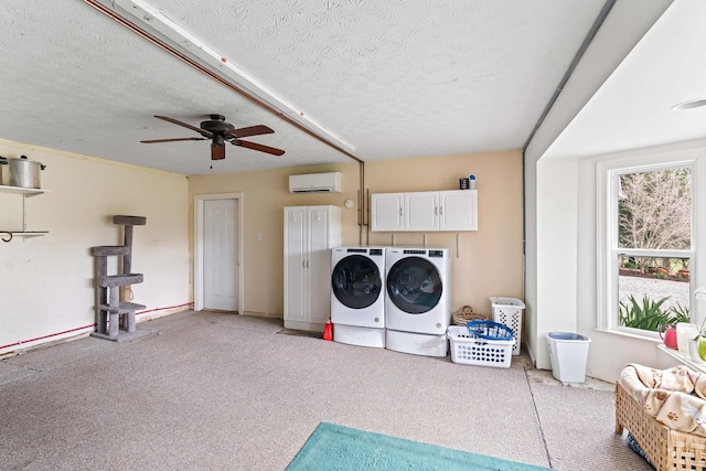 laundry area with ceiling fan, cabinets, a wall mounted air conditioner, independent washer and dryer, and a textured ceiling