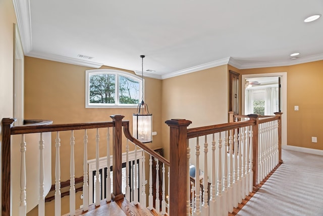 hall with a chandelier, light carpet, and crown molding