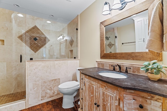 bathroom with an enclosed shower, toilet, vanity, tile walls, and hardwood / wood-style flooring