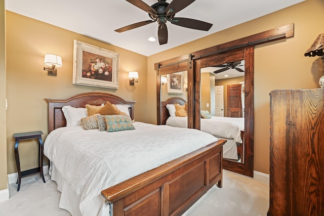 bedroom featuring ceiling fan, a barn door, and light carpet