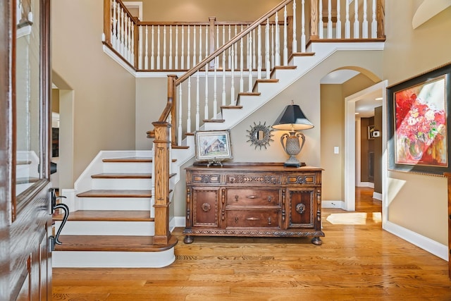 stairs with hardwood / wood-style floors and a towering ceiling