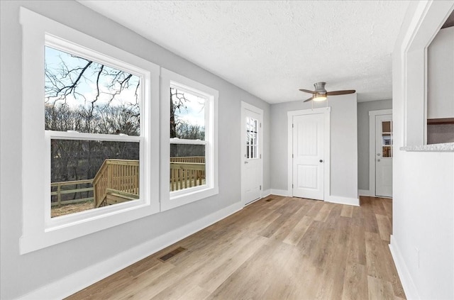 unfurnished sunroom featuring visible vents and a ceiling fan