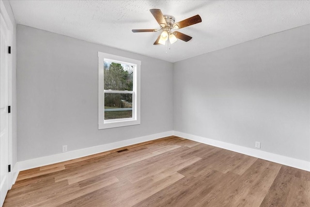 unfurnished room with baseboards, a textured ceiling, wood finished floors, and a ceiling fan