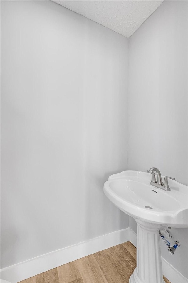 bathroom featuring wood finished floors, baseboards, and a textured ceiling