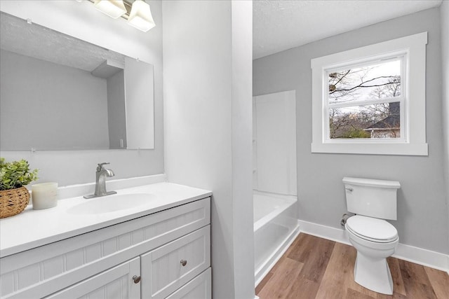 full bathroom with toilet, a textured ceiling, wood finished floors, baseboards, and vanity