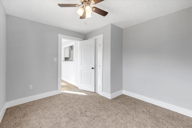 carpeted empty room with ceiling fan, a textured ceiling, and baseboards