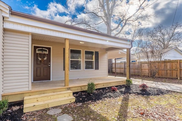 entrance to property featuring covered porch and fence