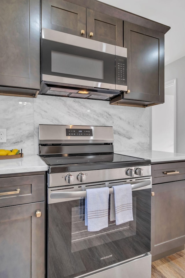 kitchen with backsplash, dark brown cabinets, stainless steel appliances, and light wood-type flooring