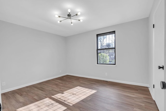 empty room with a notable chandelier and hardwood / wood-style flooring