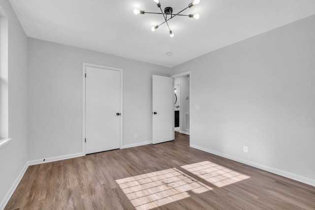 unfurnished bedroom featuring an inviting chandelier and light hardwood / wood-style flooring