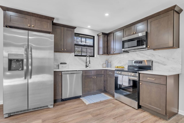 kitchen featuring sink, dark brown cabinetry, stainless steel appliances, and light hardwood / wood-style flooring