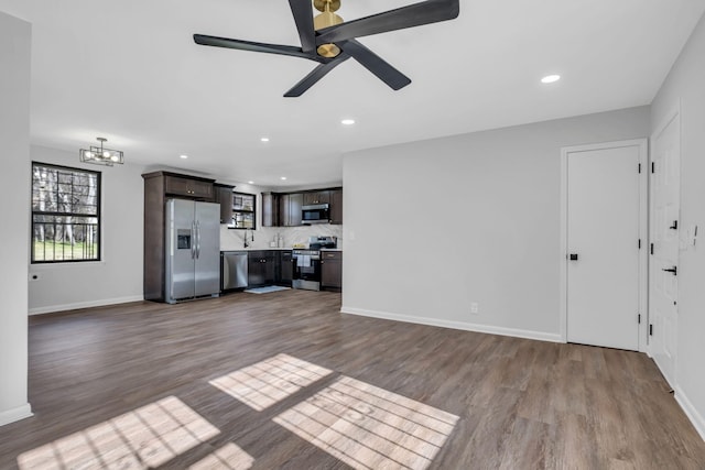 unfurnished living room featuring ceiling fan with notable chandelier and light hardwood / wood-style floors