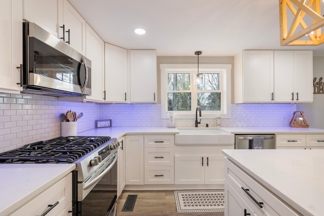 kitchen with decorative backsplash, stainless steel appliances, sink, decorative light fixtures, and white cabinets