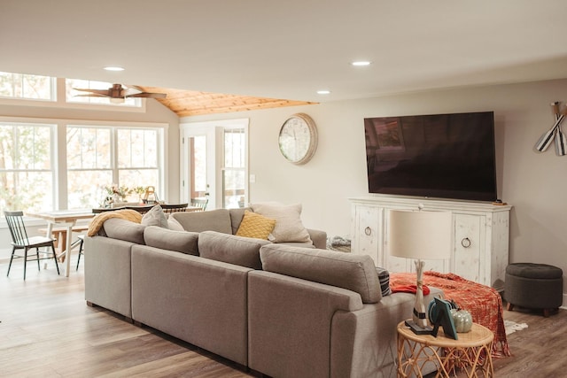 living room featuring ceiling fan, light hardwood / wood-style flooring, and vaulted ceiling