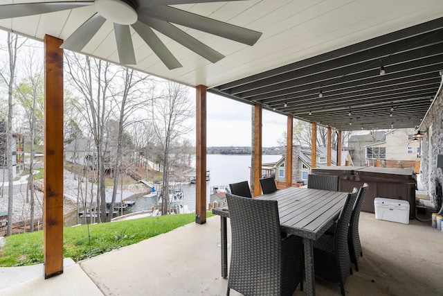 view of patio featuring ceiling fan, a water view, and a hot tub