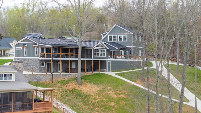 rear view of property with a sunroom, a deck, and a yard