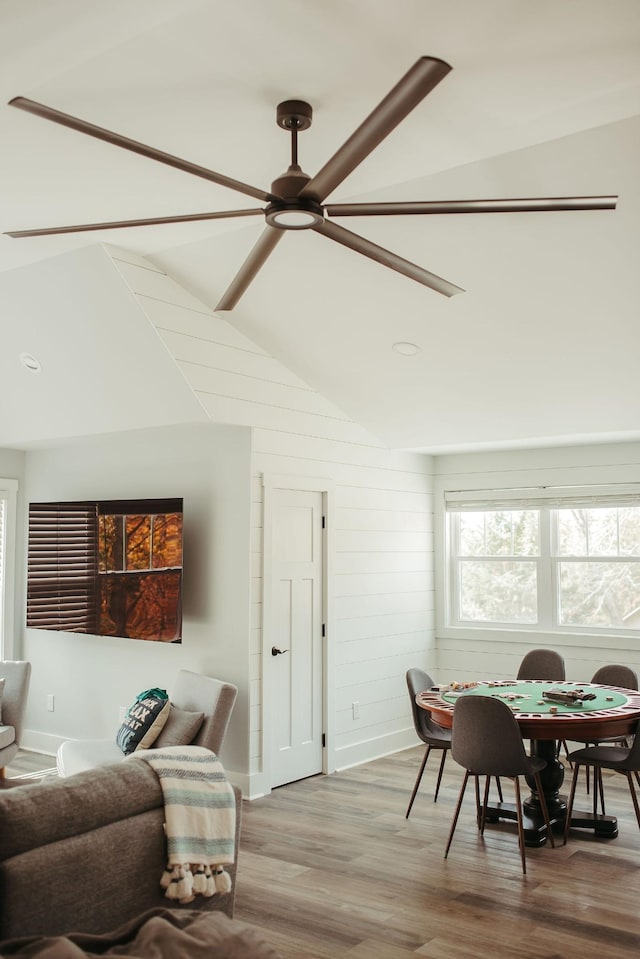 interior space featuring hardwood / wood-style flooring, ceiling fan, lofted ceiling, and wood walls