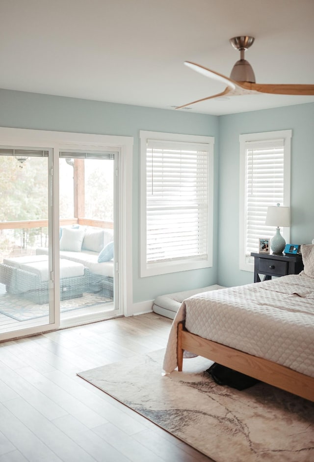 bedroom with access to exterior, wood-type flooring, multiple windows, and ceiling fan