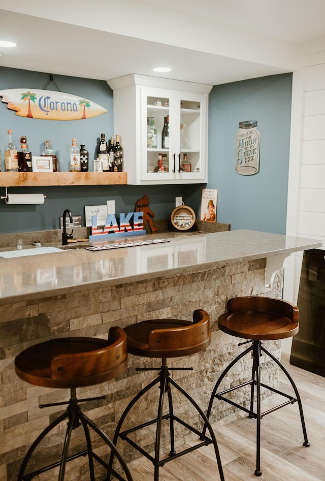 bar featuring light hardwood / wood-style flooring and white cabinetry