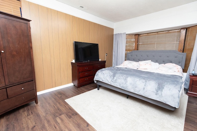 bedroom with dark hardwood / wood-style floors and wood walls