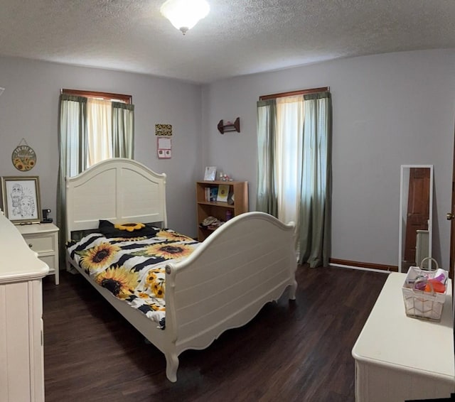 bedroom with a textured ceiling, dark wood-type flooring, and multiple windows