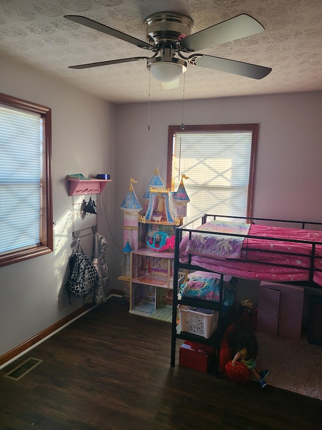 bedroom featuring multiple windows, a textured ceiling, dark hardwood / wood-style flooring, and ceiling fan