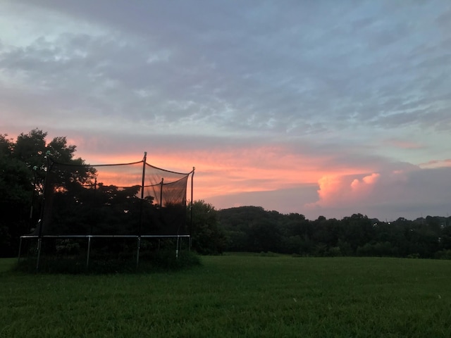 yard at dusk featuring a trampoline