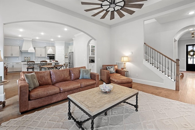 living room with light hardwood / wood-style floors, crown molding, and sink