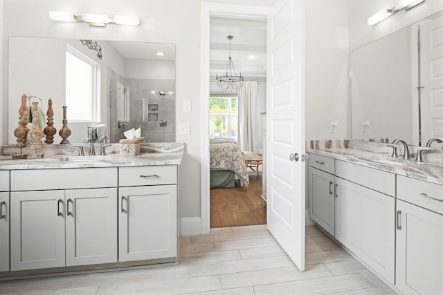 bathroom with tiled shower, tile patterned floors, vanity, and an inviting chandelier