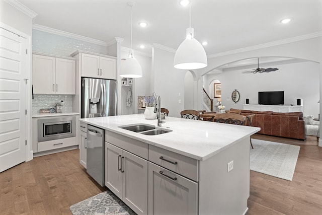 kitchen featuring sink, an island with sink, decorative light fixtures, white cabinetry, and stainless steel appliances