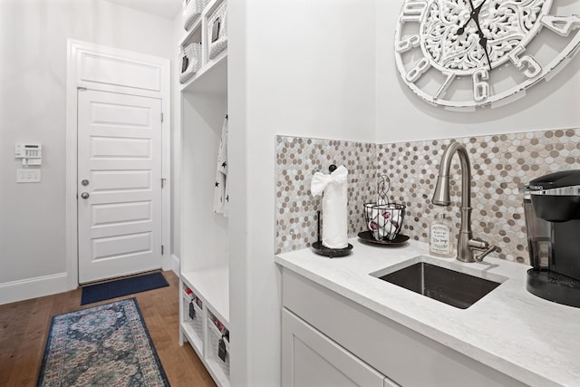 interior space with sink, dark hardwood / wood-style floors, decorative backsplash, light stone countertops, and white cabinetry