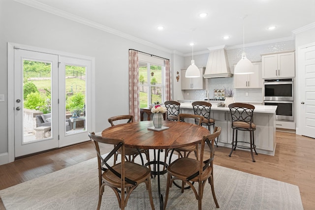 dining area with light hardwood / wood-style floors, crown molding, and a wealth of natural light