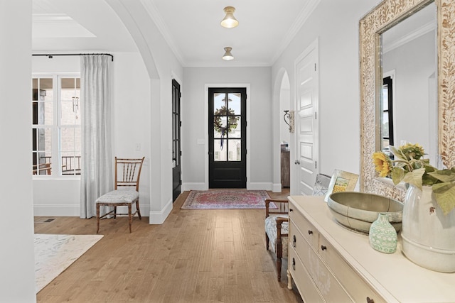 entryway featuring ornamental molding, a wealth of natural light, and light hardwood / wood-style flooring