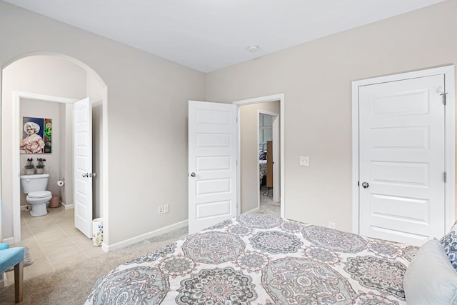 bedroom with ensuite bath and light tile patterned flooring