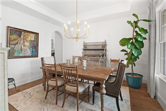 dining area featuring hardwood / wood-style flooring, a raised ceiling, crown molding, and a chandelier