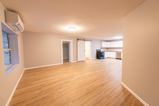 unfurnished living room featuring a barn door, light hardwood / wood-style flooring, and a wall mounted air conditioner