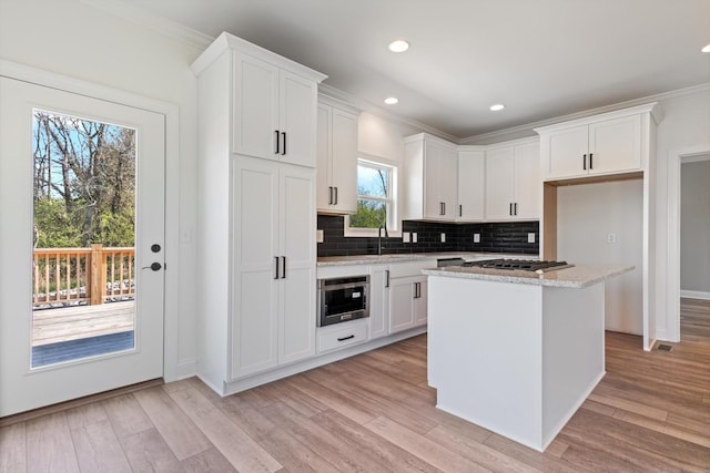 kitchen featuring white cabinetry, a center island, light stone countertops, and light hardwood / wood-style flooring