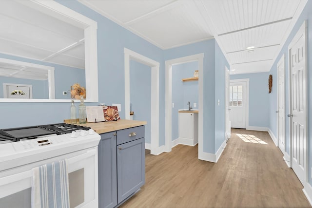 kitchen featuring gray cabinets, white range with gas stovetop, light wood-style flooring, and baseboards